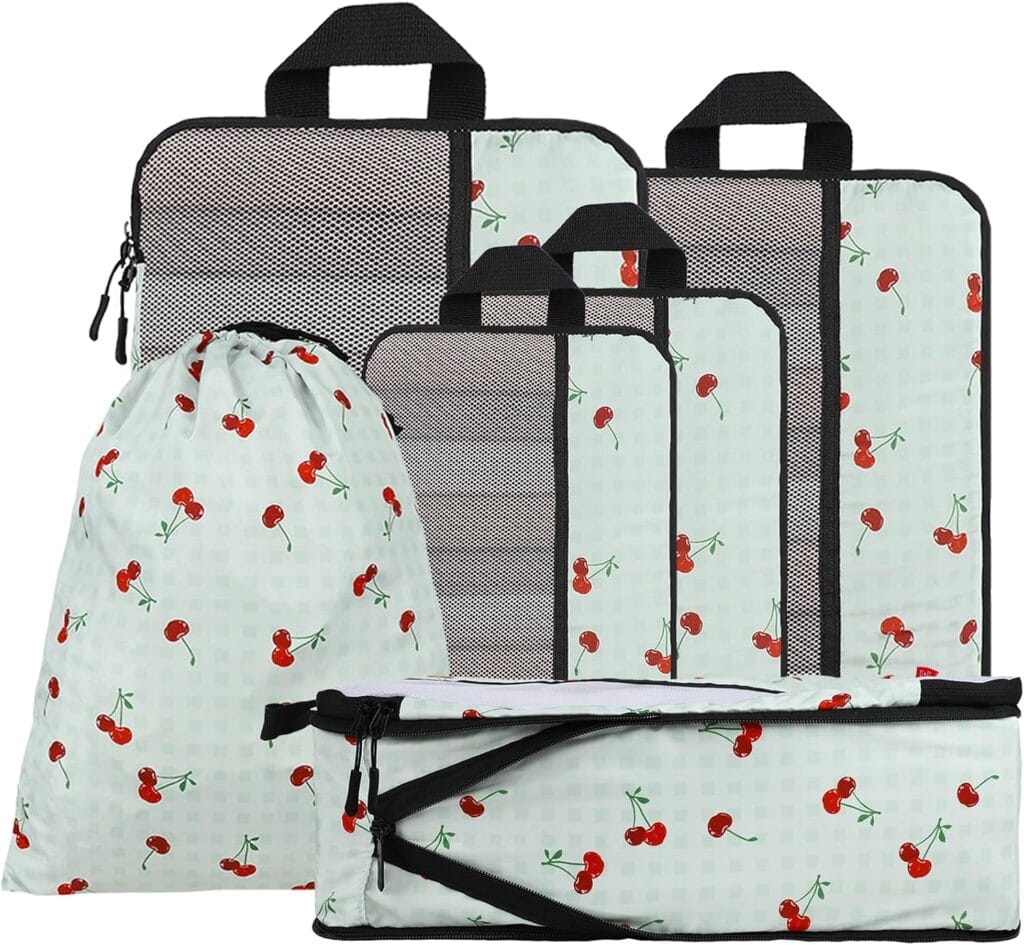 A set of six travel packing cubes and bags in various sizes, all featuring a light green checkered pattern with red cherries and black zippers and handles.