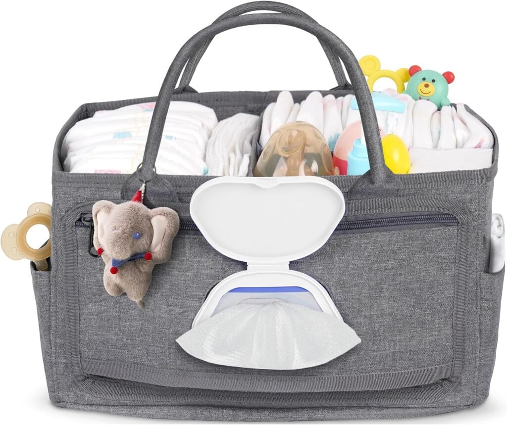 A gray diaper caddy filled with baby essentials like diapers, bottles, wipes, a pacifier, toys, and a plush elephant, with an open wipes dispenser on the front.