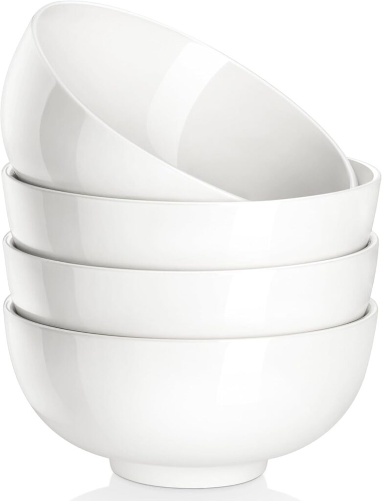 Four white ceramic bowls stacked neatly on top of each other against a plain white background.
