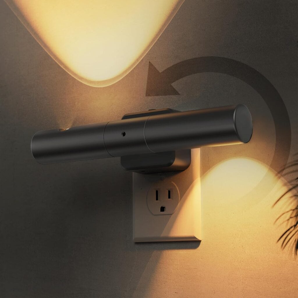 A modern black wall-mounted light fixture plugged into an outlet, casting a warm, adjustable beam upwards and downwards on a textured wall with a plant shadow nearby.