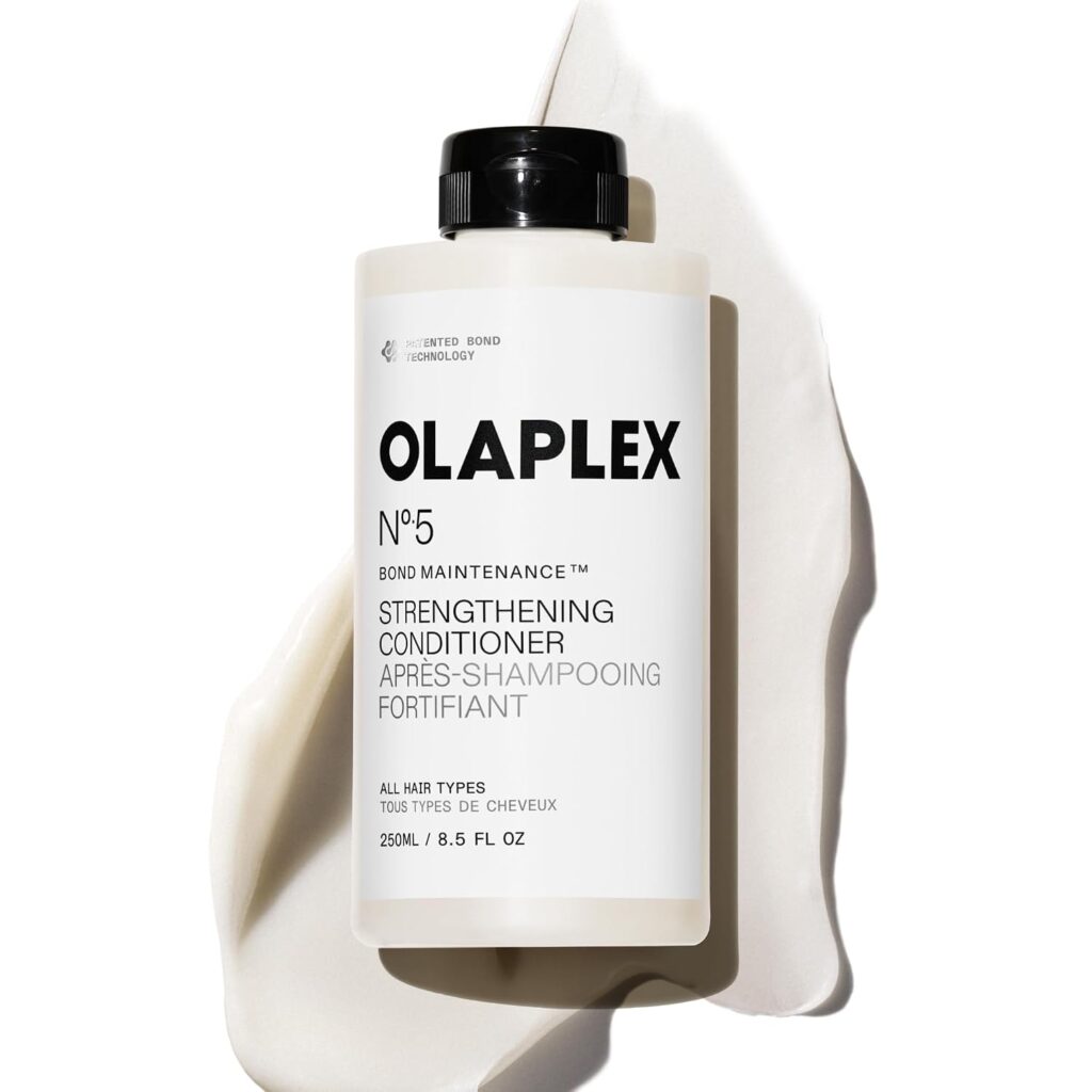 A bottle of Olaplex No. 5 Bond Maintenance Strengthening Conditioner sits on a creamy white background. The bottle is white with a black cap and clear labeling on the front.
