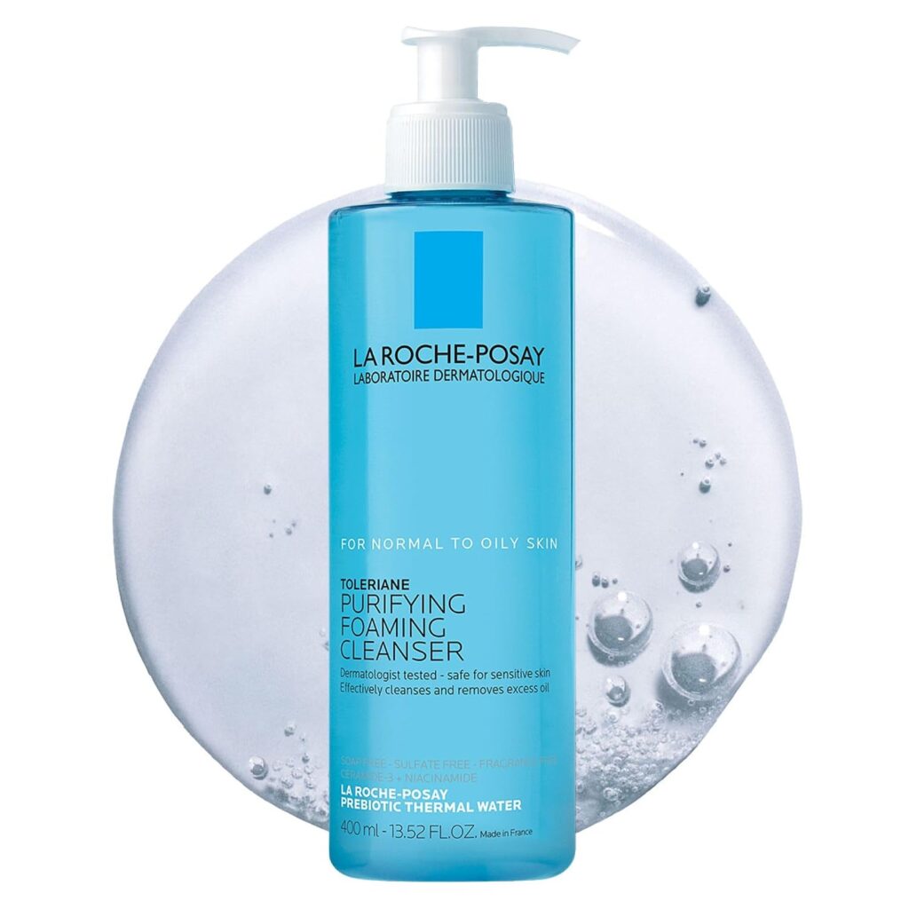 A blue bottle of La Roche-Posay Purifying Foaming Cleanser with a pump, placed in front of a clear, bubbly gel smear. The label indicates it is for normal to oily skin and contains 13.52 fl oz.