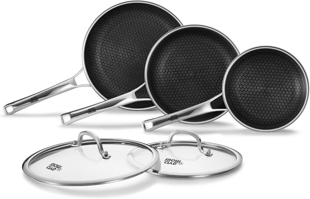 Three stainless steel non stick frying pans with black honeycomb-patterned interiors are shown behind two matching glass lids. The frying pans set is arranged from largest to smallest, all with sleek metal handles.