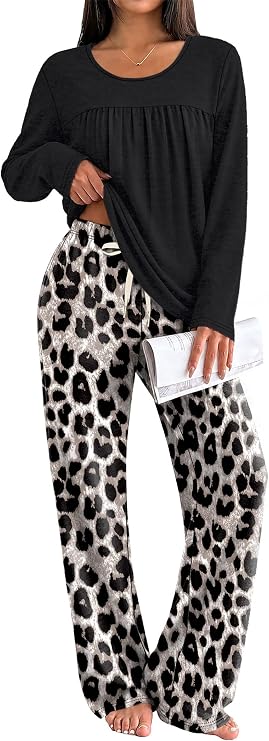 Woman wearing a black long-sleeve top and loose, white and black leopard print pants, holding a white clutch and standing barefoot.