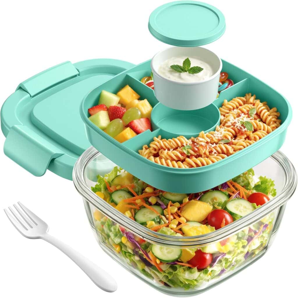 A teal bento lunch box with fruit, pasta, dip, and a salad in a glass container below—perfect for fresh meals on the go. A white fork is placed beside the box. Don’t miss out on our Monday Deals to make your lunchtime even better!.