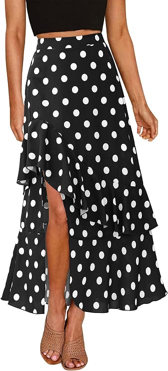 Woman wearing a black high-waisted skirt with large white polka dots, ruffled layers, and a front slit, paired with a black crop top and woven heels.