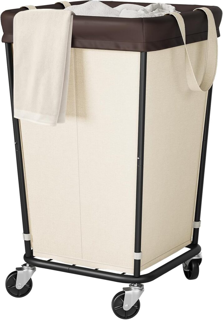 A tall, beige laundry hamper with a dark brown rim, black metal frame, and four wheels—now featured in our Monday Deals. A cream-colored towel hangs over the side, and a fabric strap is looped over the top edge.
