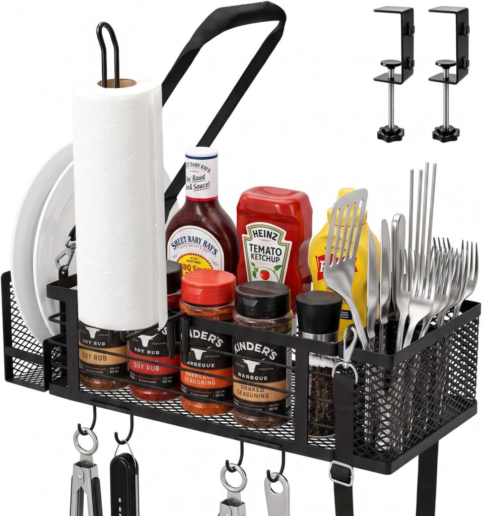 A black metal rack holds plates, paper towels, condiments, spices, utensils, and grilling tools—perfect for organizing your outdoor cooking essentials. Two clamps are shown for mounting the rack to a surface. Take advantage of Monday Deals to upgrade your grilling setup with this versatile rack.