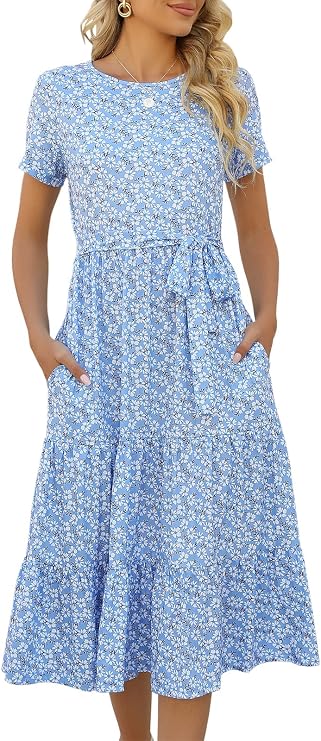Woman wearing a light blue, short-sleeve, floral Women’s Summer Dress with a waist tie and pockets. She has long, wavy blonde hair and is accessorized with earrings and a necklace, creating the perfect casual midi dress look for any occasion.