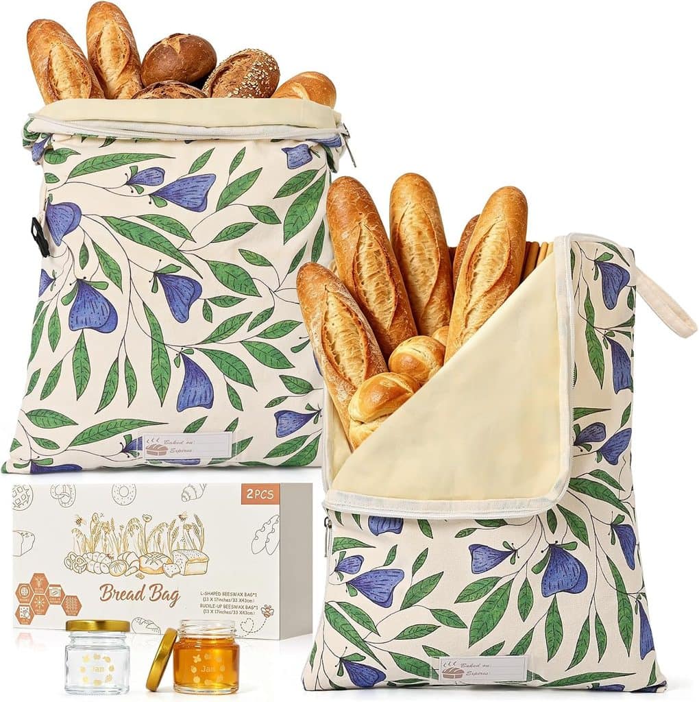 Two floral-patterned bread bags filled with baguettes and rolls are displayed next to a matching box and two small jars of honey. The bags have blue, green, and beige designs and are made for storing fresh bread—perfect for keeping your bakery favorites at their best. Don’t miss out on Wednesday Deals to add these charming essentials to your kitchen collection.
