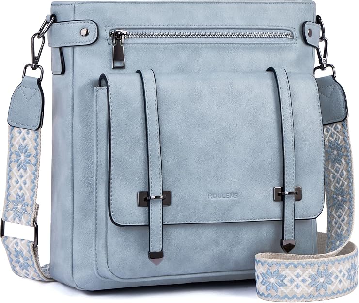 Light blue crossbody bag with a decorative front pocket, silver zippers, and a patterned adjustable shoulder strap featuring white and blue designs.