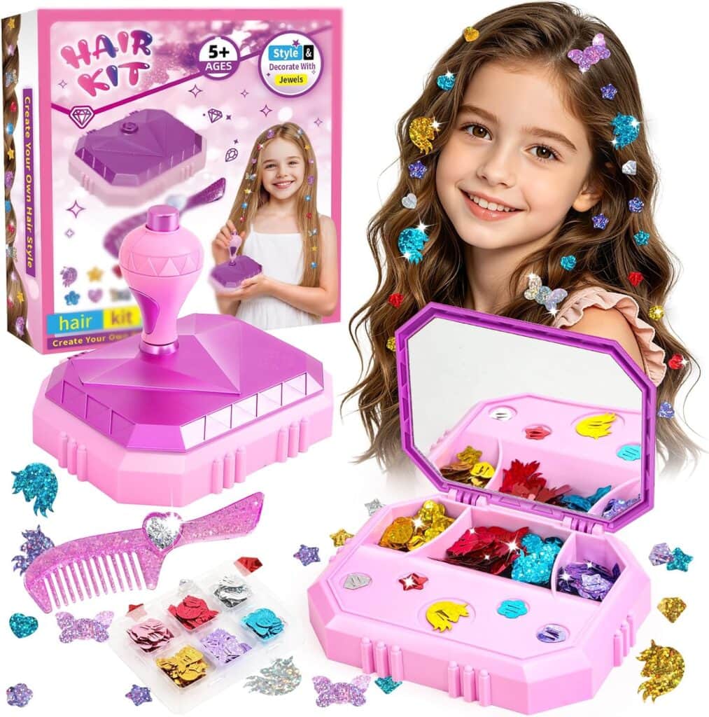 Hair Gem Stamper Kit for ages 5+, featuring a pink case with a mirror, sections of colorful hair jewels, a purple comb, and an image of a smiling girl with hair jewels. Box shows product details and creative design ideas for using the included hair accessories.