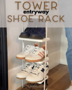 A three-tier white shoe rack in an entryway holds various pairs of sneakers and boots. The rack is placed on a wooden floor near a black door. Text reads “Tower entryway shoe rack.”.