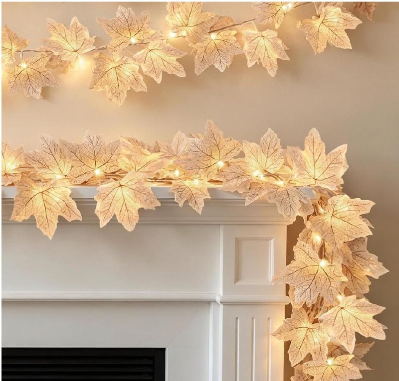 A lighted garland of orange and red fall maple leaves draped across a mantel, featured in our Thursday Deals.