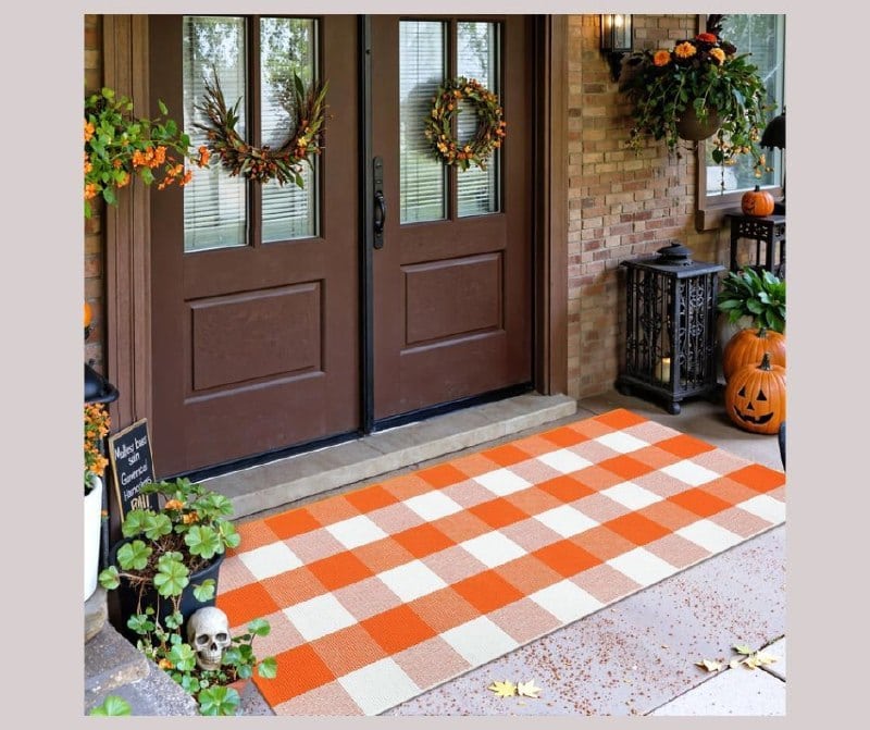 A black and white buffalo plaid outdoor rug layered on a fall front porch, featured in our Monday Deals.
